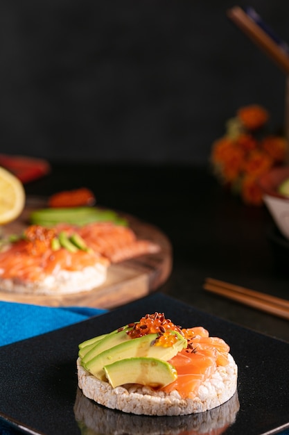 Puffreisaufstrich mit rohem Lachs und Avocado auf einem dunklen Tisch