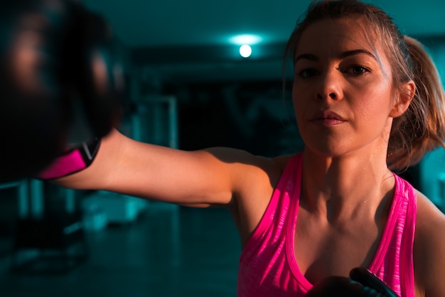 Pugilista fêmea que pratica seus movimentos. Fechar-se. Olhando para a câmera.