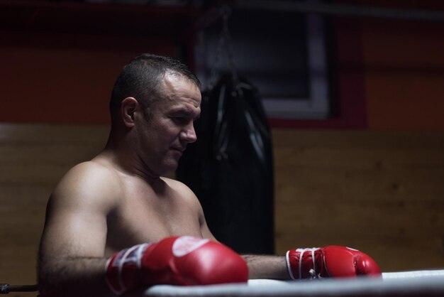 Pugilista profissional musculoso descansando nas cordas no canto do ringue enquanto treinava para a próxima partida