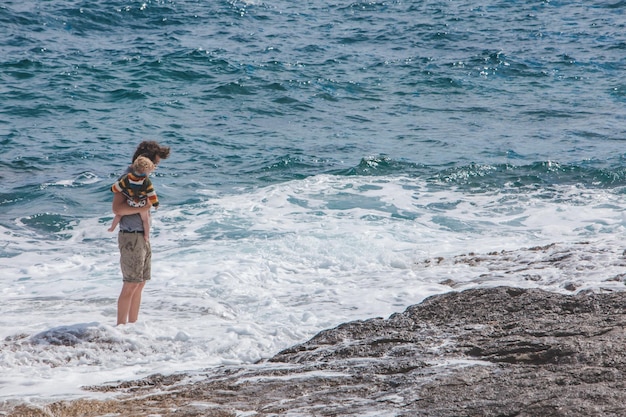 PULA CROACIA 20 de mayo de 2019 joven padre sosteniendo a un niño en las manos mostrando olas en el mar