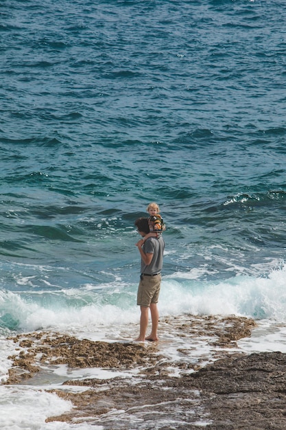 PULA CROACIA 20 de mayo de 2019 joven padre sosteniendo a un niño sobre los hombros caminando por la playa del mar