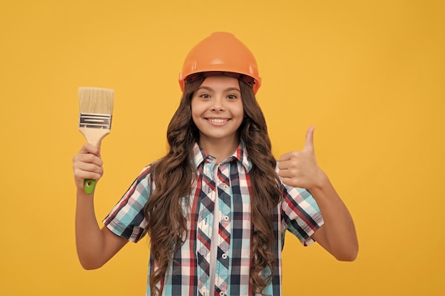 Pulgar hacia arriba para el éxito feliz jovencita mantenga pincel niño pintor en casco