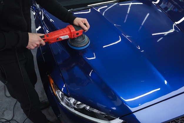 Foto pulido de coche después de pintar. detallando coche desde el exterior. dispositivo para pulir en las manos.