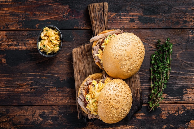 Pulled Pork Burger mit BBQ-Sauce und Krautsalat. Dunkler hölzerner Hintergrund. Ansicht von oben.