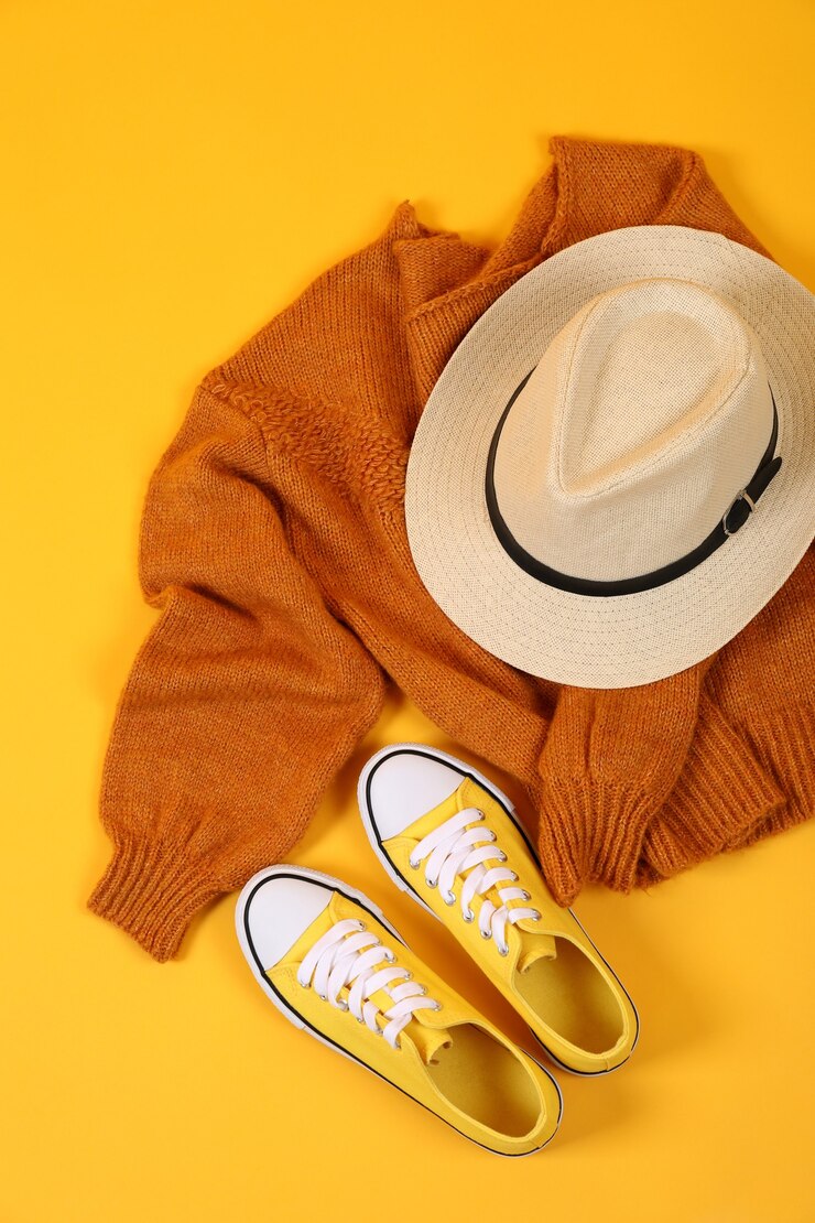 Foto pullover, turnschuhe und hut auf gelbem hintergrund.