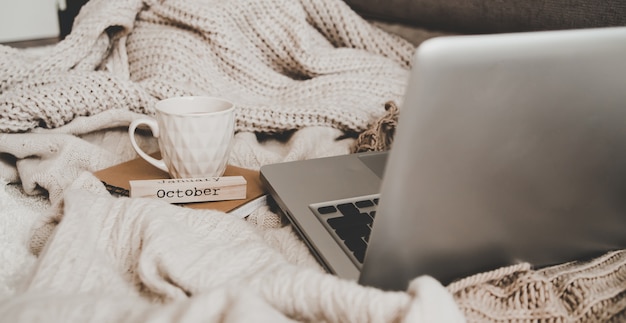 Pullover und eine Tasse Tee mit Notebook, Laptop und Strickkleidung