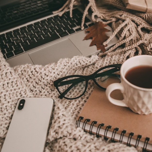 Pullover und eine Tasse Tee mit Notebook, Laptop und Telefon