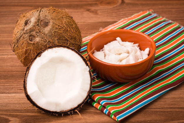 Pulpa de coco en un bol y cocos en una mesa de madera