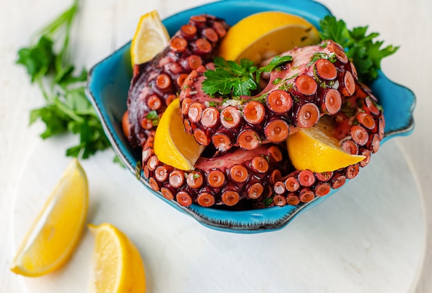 Pulpo adobado cocinado en un recipiente azul sobre fondo blanco. Copia espacio, vista superior. cocina asiática