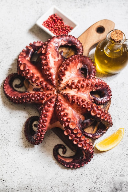 Foto pulpo entero hervido sobre piedra gris con limón y pimienta rosa