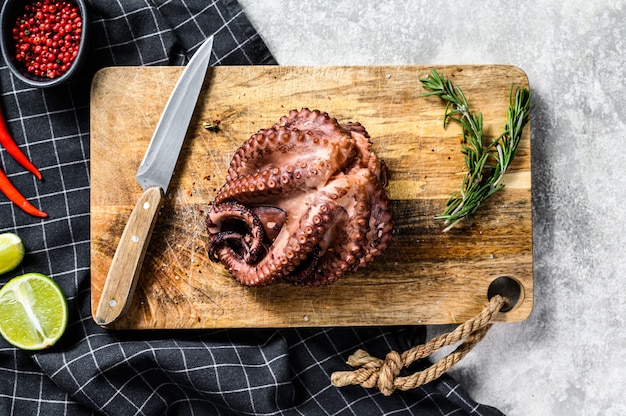 Pulpo entero a la parrilla sobre una tabla para cortar. Vista superior