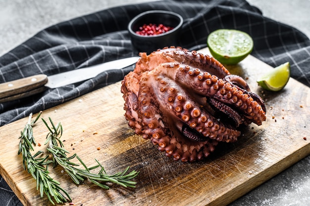 Pulpo entero a la parrilla sobre una tabla para cortar.