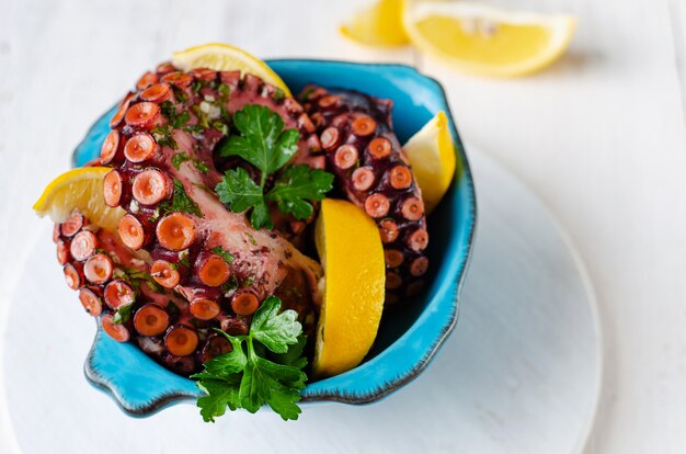 Pulpo hervido con limón y perejil en un recipiente azul