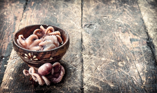 Pulpo marinado en un cuenco sobre una mesa de madera.