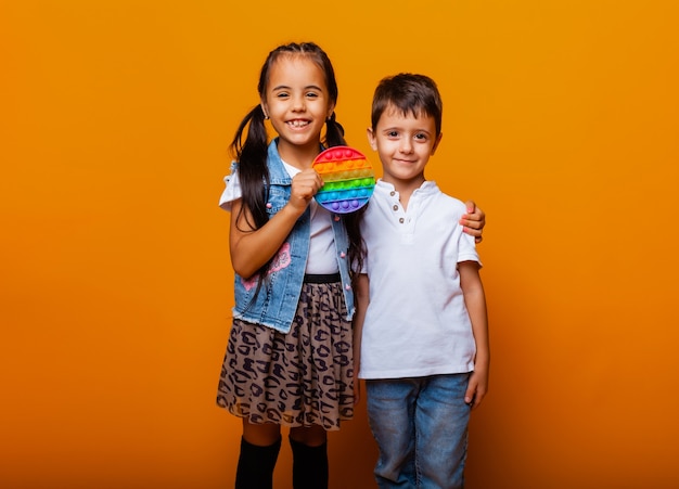 Pulsador de juguete de silicona antiestrés. los niños juegan con pop sobre un fondo amarillo.