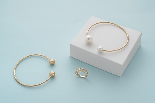 Pulseira de ouro com pérolas na caixa branca e pulseira e anel de ouro com espaço de cópia