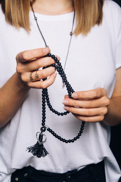 Pulsera de abalorios negros en mano niña. Se puede usar como accesorios de moda, también como cuentas de oración, para contar oraciones o practicar la meditación de atención plena. Algunos creen que la piedra negra tiene poder de protección.