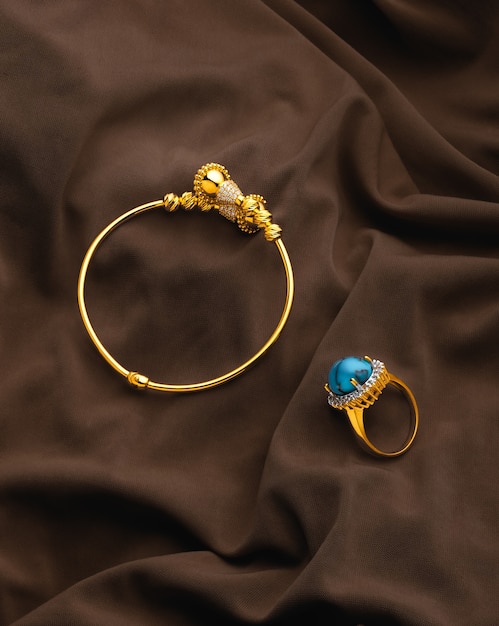 Foto pulsera y anillo dorado sobre tela raída