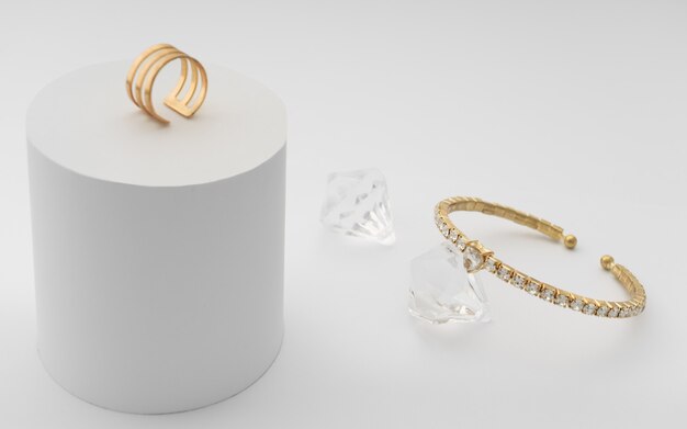 Pulsera de diamantes dorados y anillo en superficie blanca