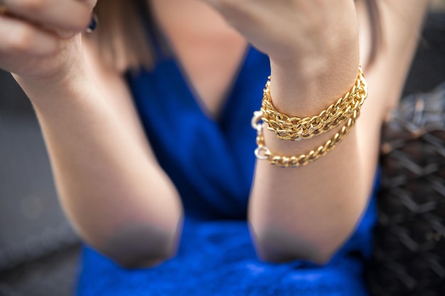 Pulsera en forma de cadena en la muñeca de una mujer con un vestido azul.