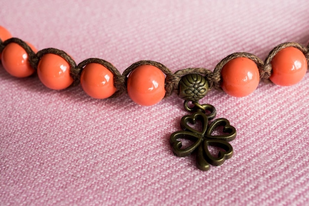 Una pulsera naranja con un colgante de trébol.