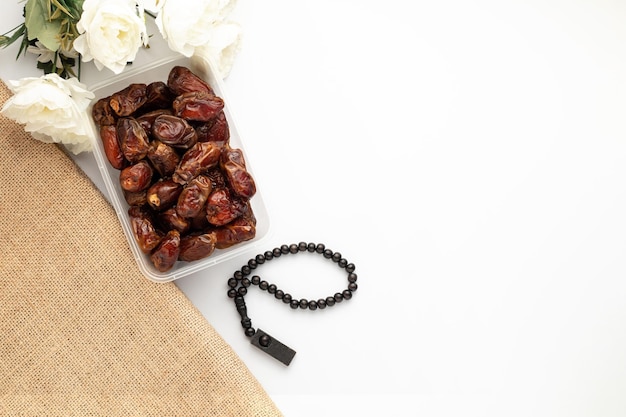 Una pulsera negra y flores blancas con dátiles sobre fondo blanco.