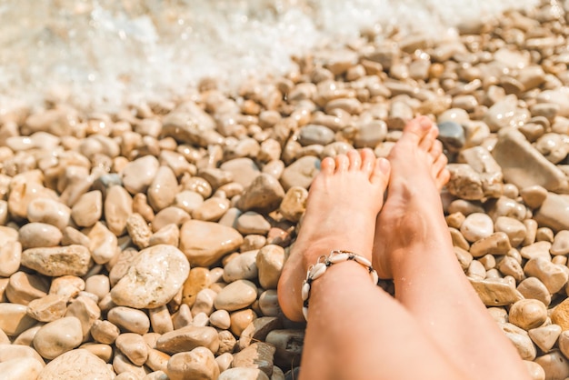 Pulsera en piernas mujer en la playa del mar