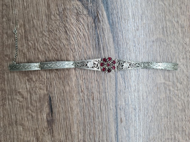 Pulsera de plata con flor roja en la parte delantera.