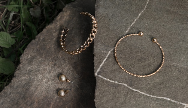 Pulseras y aretes de oro con forma de cadena y espiral sobre fondo de roca natural con espacio de copia