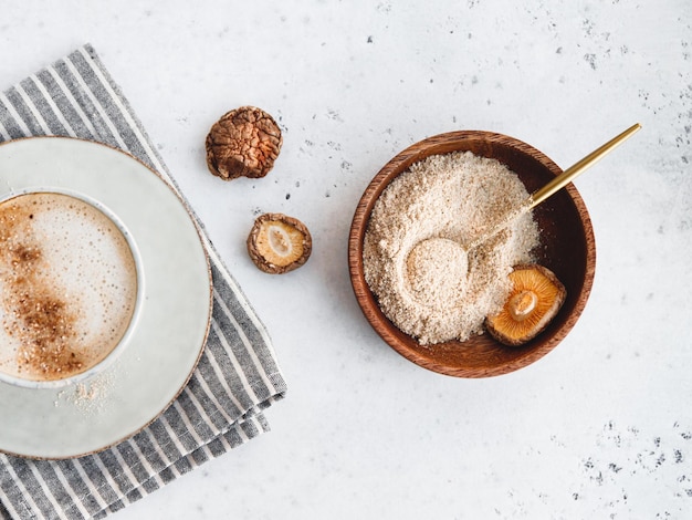 Pulver wird aus chinesischen getrockneten Pilzen Shiitake in einer Holzschale auf einem Tisch hergestellt Das Konzept des medizinischen Zusatzstoffs für gesunde Lebensmittel