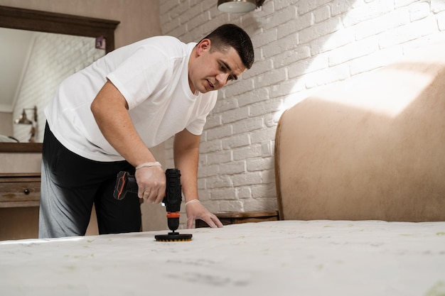 Pulverizar e espalhar detergente no colchão branco usando broca com escova para limpeza a seco Aplicação de detergente no colchão para limpeza a seco