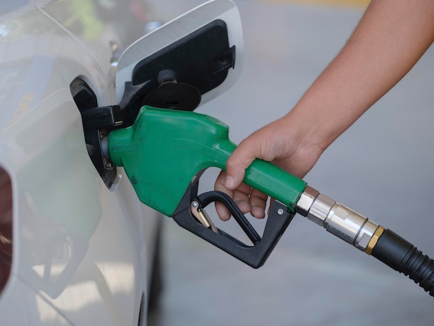 Pumpen von Benzin an der Zapfsäule Nahaufnahme eines Mannes, der Benzin in ein Auto an einer Tankstelle pumpt