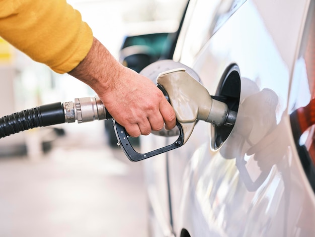 Pumpen von Gas an der Zapfsäule. Nahaufnahme eines Mannes, der Benzin in ein Auto an einer Tankstelle pumpt.