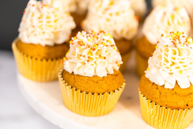 Pumpkin Spice Cupcake mit italienischer Buttercreme und Streuseln auf einem Tortenständer.