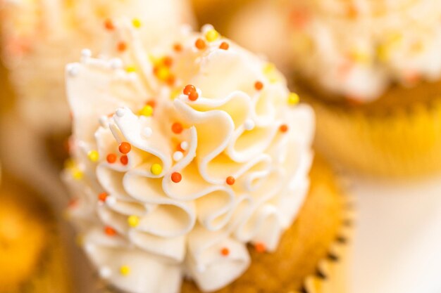 Pumpkin Spice Cupcake mit italienischer Buttercreme und Streuseln auf einem Tortenständer.