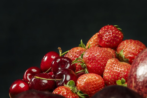 Un puñado de cerezas rojas en un platillo negro junto