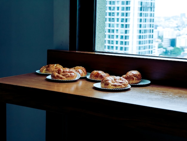 Foto un puñado de deliciosos cruasanes, el desayuno francés preparado en un escritorio de madera.