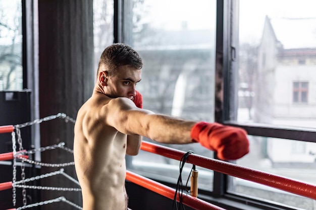 Punhing hombre con vendas rojas en el ring