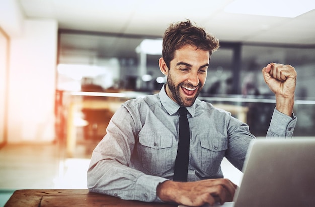 Foto punho de homem de negócios e celebração com laptop ganhando ou promoção na inicialização com rosto animado jovem empresário vencedor e comemorando com bônus de computador ou lucro em investimento no mercado de ações