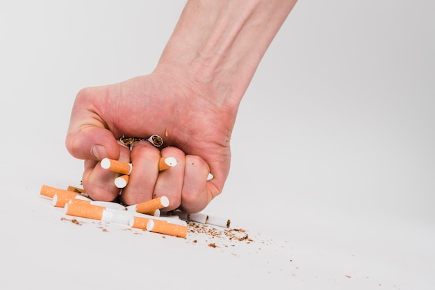 Punho de um homem esmagando cigarros sobre fundo branco