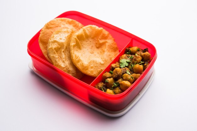 Punjabi Chole o Choley masala con puri o poori en lonchera o tiffin, enfoque selectivo