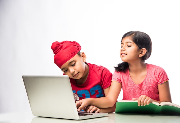 Punjabi sij indio niño y niña estudiando con libros y computadora portátil en la mesa de estudio