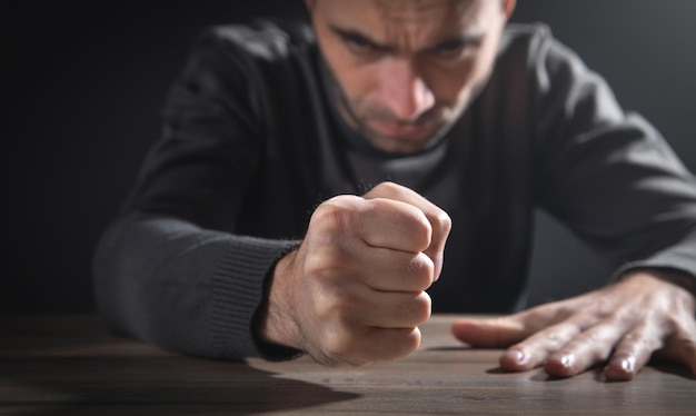 Puño de hombre enojado golpea sobre la mesa.