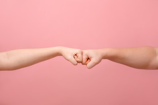 Puño de manos de hombre y mujer sobre fondo rosa