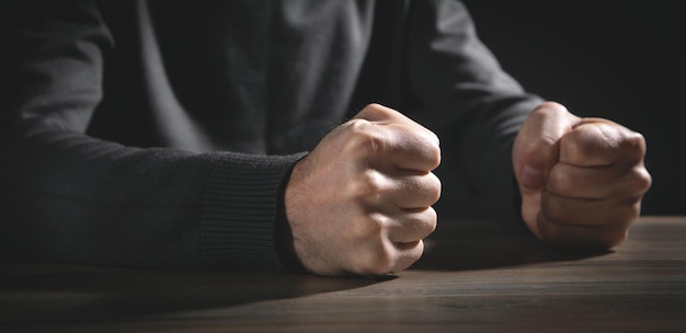 Puños de hombre enojado golpea sobre la mesa.