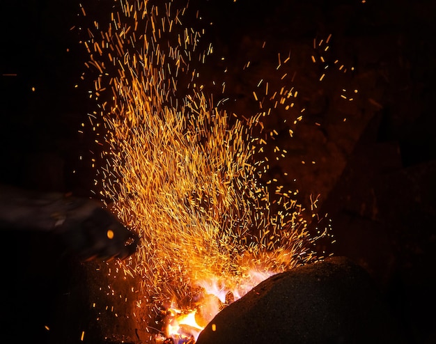 Puntas de llama de fuego de herrería con chispas de primer plano sobre fondo oscuro