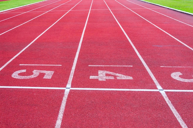 Punto de partida de los números en la pista de atletismo roja y la pista de atletismo grassDirect atletismo verde en el estadio deportivo