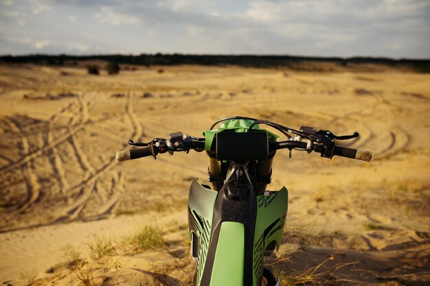 Punto de vista del conductor de motocross sobre terreno arenoso. Detalle del volante de la moto closeup