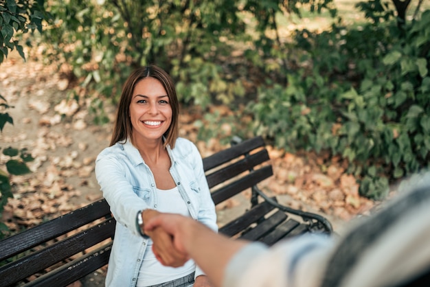 Punto de vista personal del hombre que sacude las manos con la amiga en el parque.