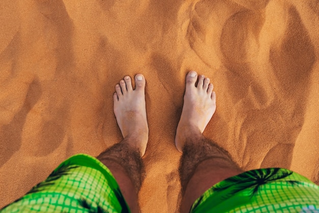 Punto de vista sobre las piernas de los hombres descalzos sobre la arena en el desierto